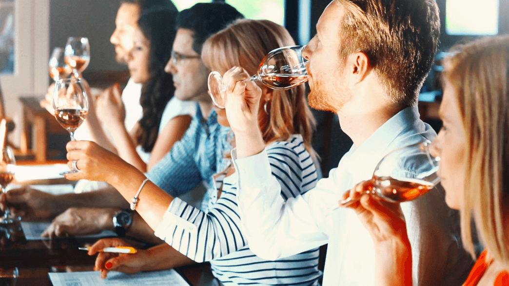 Gruppe junger Erwachsener verkostet Weißwein in stilvollem Tasting-Setting.